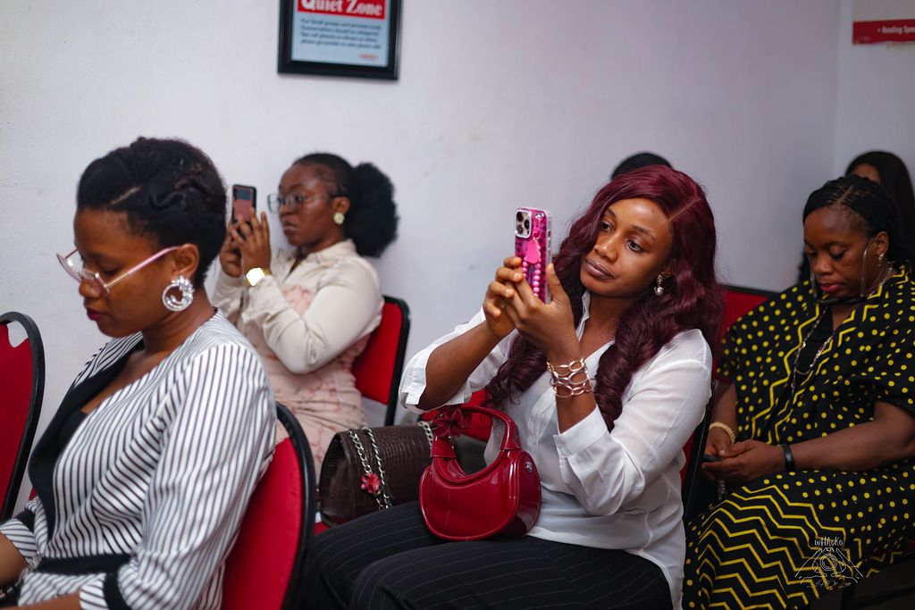 Women in the audience, one holding up a phone to record
