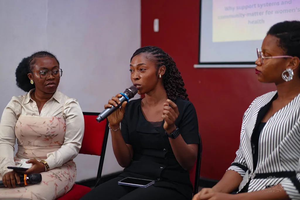 Three panellists seated together, one speaking into a microphone