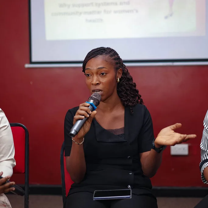 A woman answering a question into a microphone on a panel